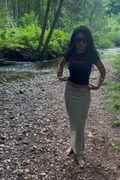young teen adult woman wearing a babytee that reads 'menace' in pink lettering. nature background and boho theme.